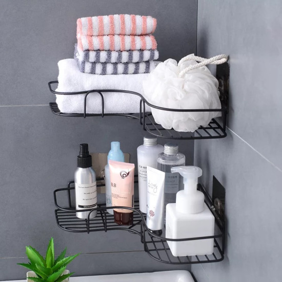 Black metal corner wall shelf with two tiers mounted on gray tiled wall. The top tier holds three folded towels in white, pink, and gray stripes, and a white bath sponge with a rope handle. The bottom tier holds various bottles and tubes including a white