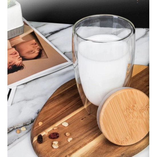 Double Wall Glass Cup with Bamboo Lid for Hot Drinks Clear double wall glass cup filled with milk next to a round bamboo lid on a wooden board
