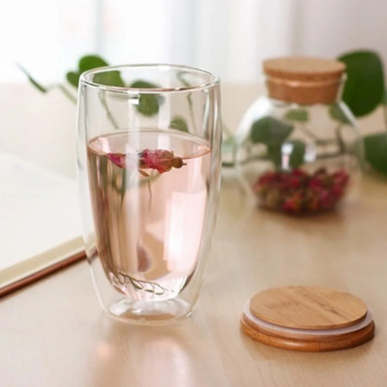 Clear Double Wall Glass Cup with Flat Bamboo Lid Clear double wall glass cup filled with pink liquid next to a flat bamboo lid on a wooden table