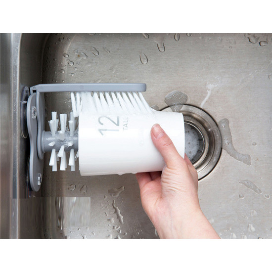 Dual-Sided Cup and Dish Cleaning Brush Hand holding white dual-sided brush cleaning inside and outside of a white cup in a kitchen sink