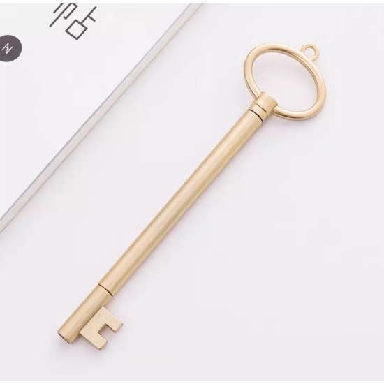 Elegant golden pen shaped like a classic key with a round top and rectangular bit on a white surface
