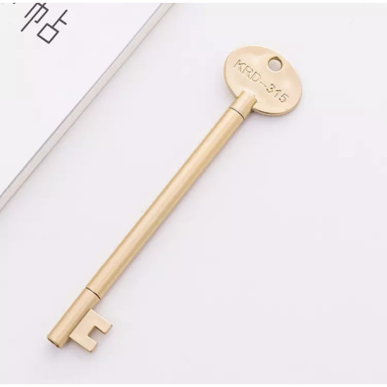 Golden pen shaped like a key with KRD engraving on the oval top on a white surface