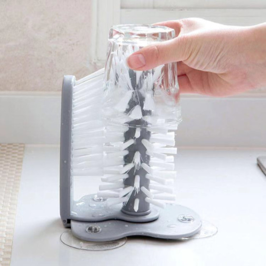 Double-Sided Cup and Dish Cleaning Brush with Gray Base Double-sided cleaning brush with white bristles and gray base holding a glass cup for simultaneous internal and external