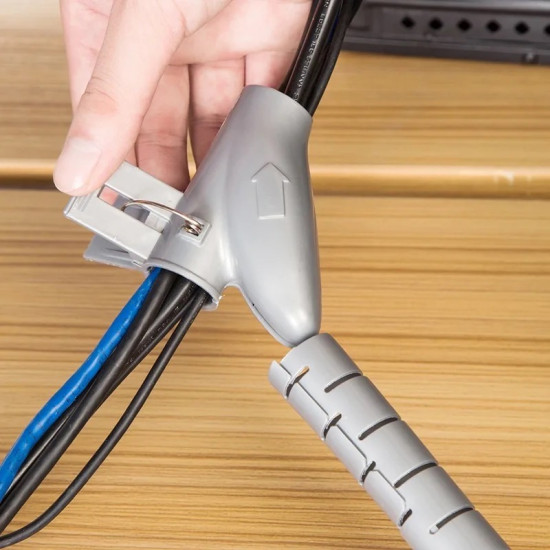 Flexible Cable Organizer Sleeve with Clip in Gray Gray flexible cable sleeve with spiral cuts and a clip organizing black and blue cables on a wooden surface