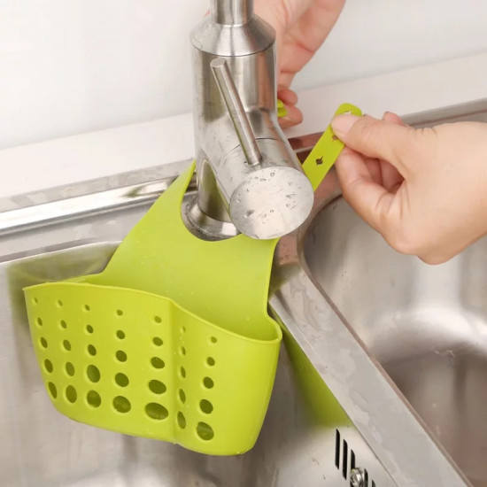 Green silicone holder with multiple holes hanging on kitchen faucet, designed for sponges or soap