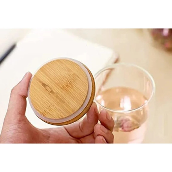 Hand holding a round bamboo lid with a white silicone ring for a glass cup