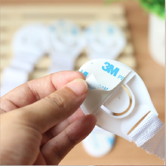 Child Safety Lock with Adhesive Backing Being Peeled Hand peeling 3M adhesive backing from a white child safety lock strap
