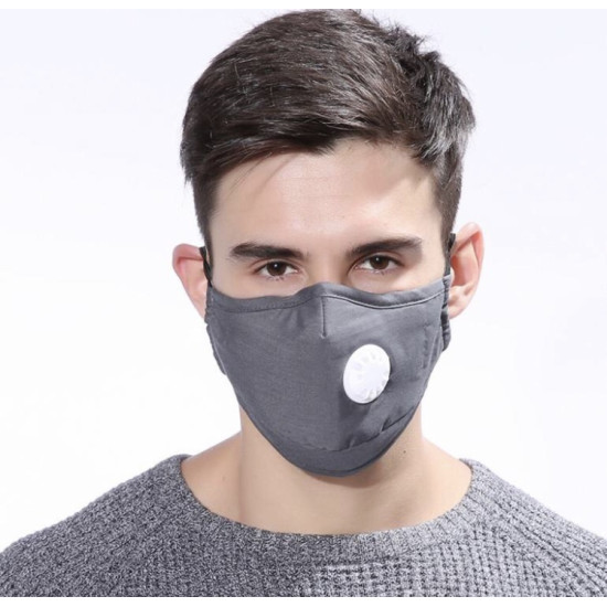 Gray face mask with white valve worn by man Front view of a man wearing a gray face mask with a white circular valve on the right side. The mask covers the nose and mouth and has ear loops visible on both sides. The man has short dark hair and is wearing a gray knitted sweater.
