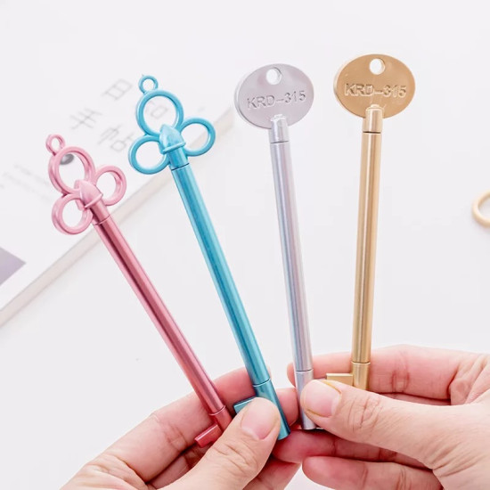 Four metallic key-shaped pens in pink, blue, silver, and gold with different top designs held in hand