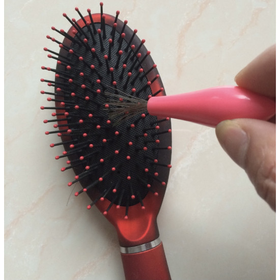 Pink handle tool with thin metal wires used to remove hair stuck in a red hairbrush
