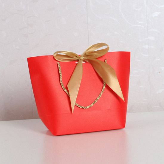 Red Paper Gift Bag with Golden Ribbon Bow Red paper gift bag with twisted golden rope handles and a large golden satin ribbon bow