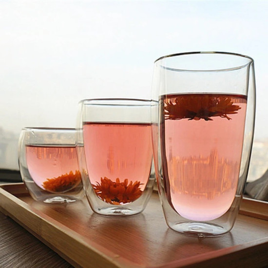 Double Wall Glass Cups with Bamboo Lid for Hot Drinks Three clear double wall glass cups filled with pink flower tea, each with a visible flower inside, placed on a wooden tray