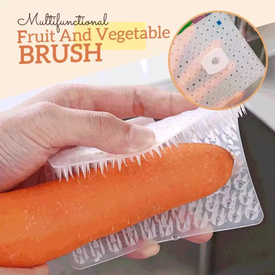 Transparent silicone brush with textured bristles cleaning a carrot held by hand