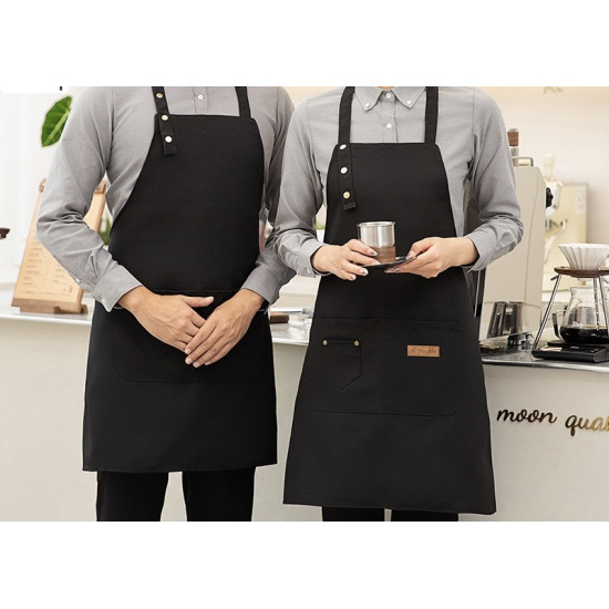 Two people wearing black aprons with buttoned neck straps and front pockets in a cafe setting