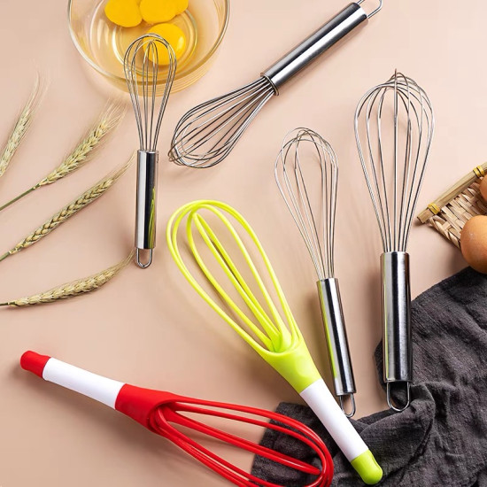Set of metal and silicone hand whisks with different handle colors and designs on beige surface